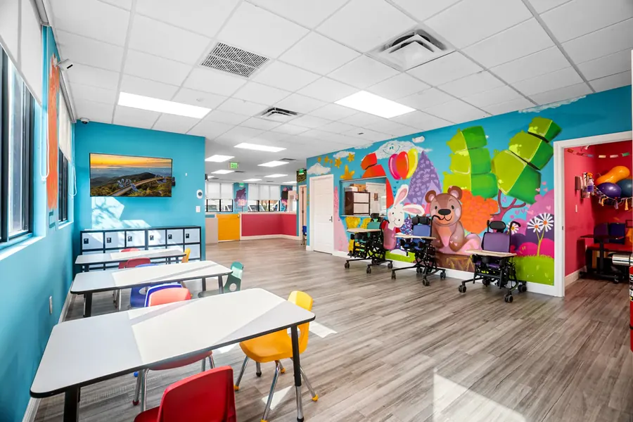 The activity and dining room at Superhero Kids PPEC, with painted balloons on the wall