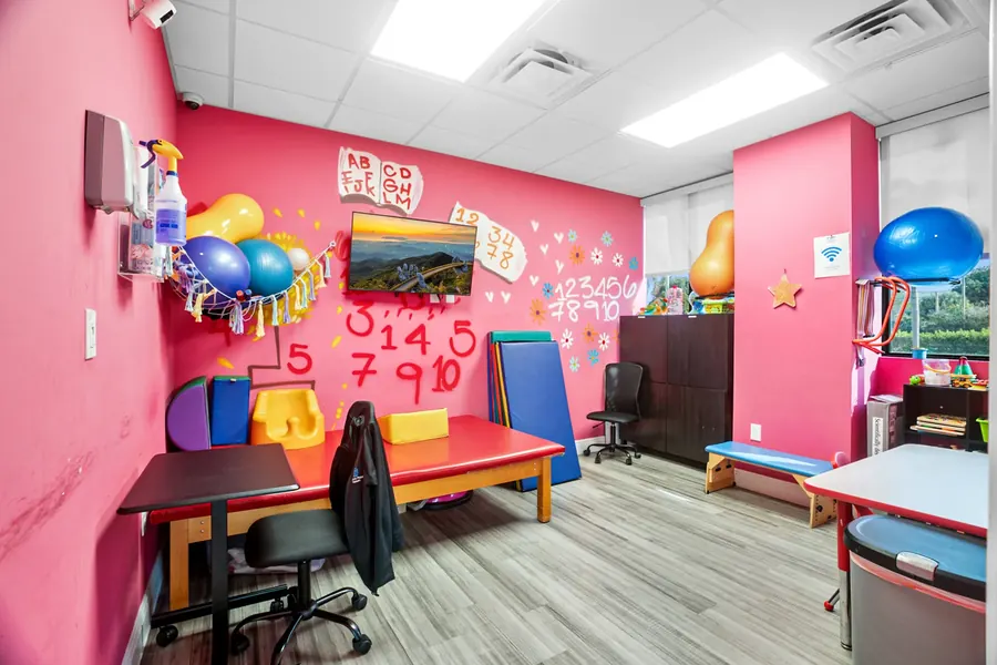 The therapy and learning room at Superhero Kids PPEC, with a red table, exercise balls and numbers painted on the wall