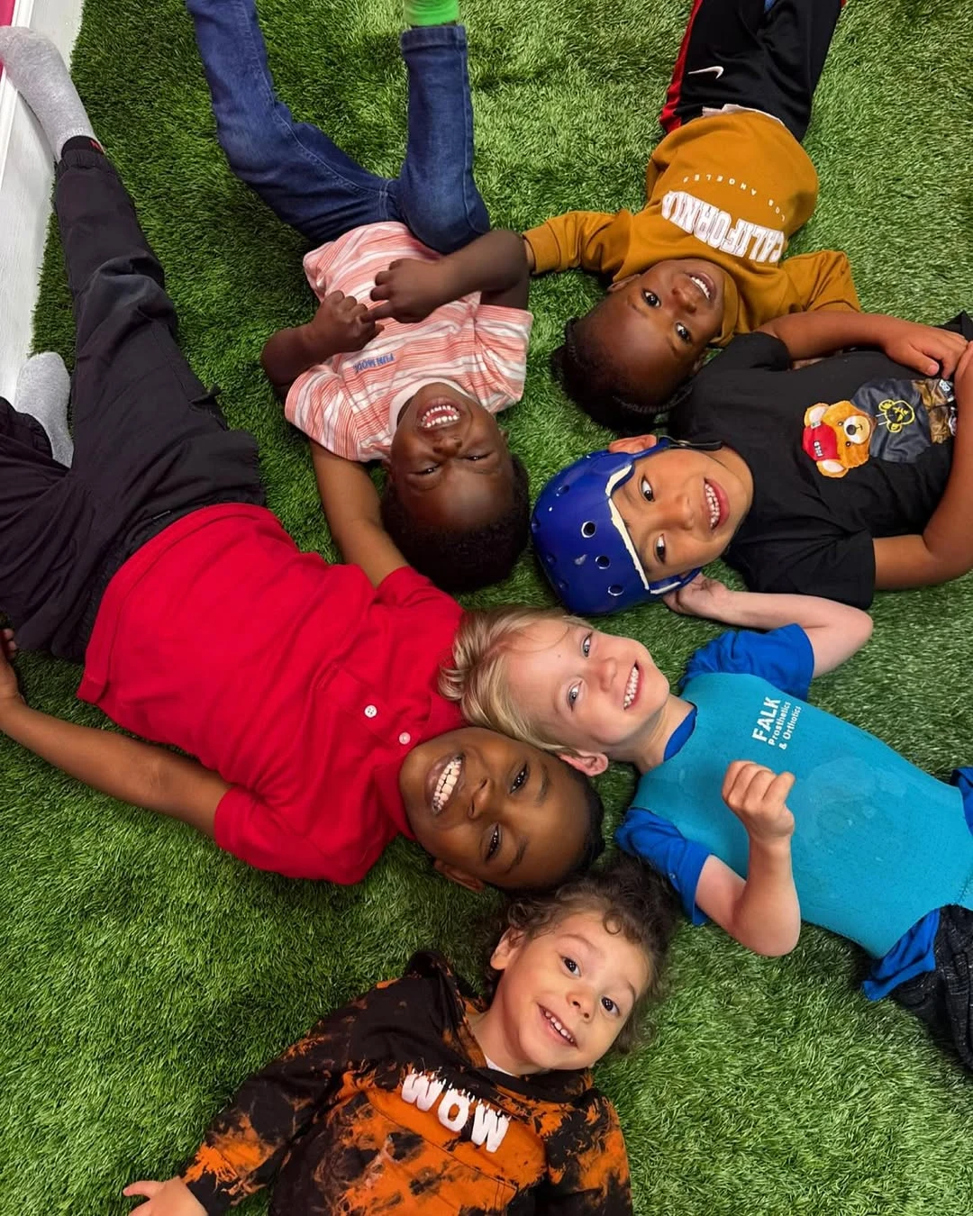 Children smiling together in a circle on the grass at Superhero Kids