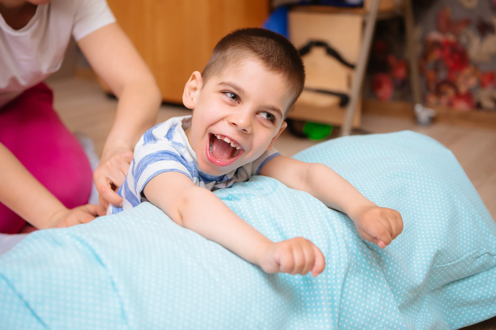 A child supported by an adult during an exercise on a therapy ball
